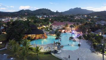 Een resort met een groot zwembad, loungegedeeltes en een bar.