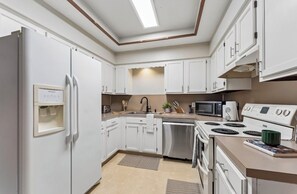 A modern kitchen with white cabinets, a built-in microwave, a stove, and a dishwasher.