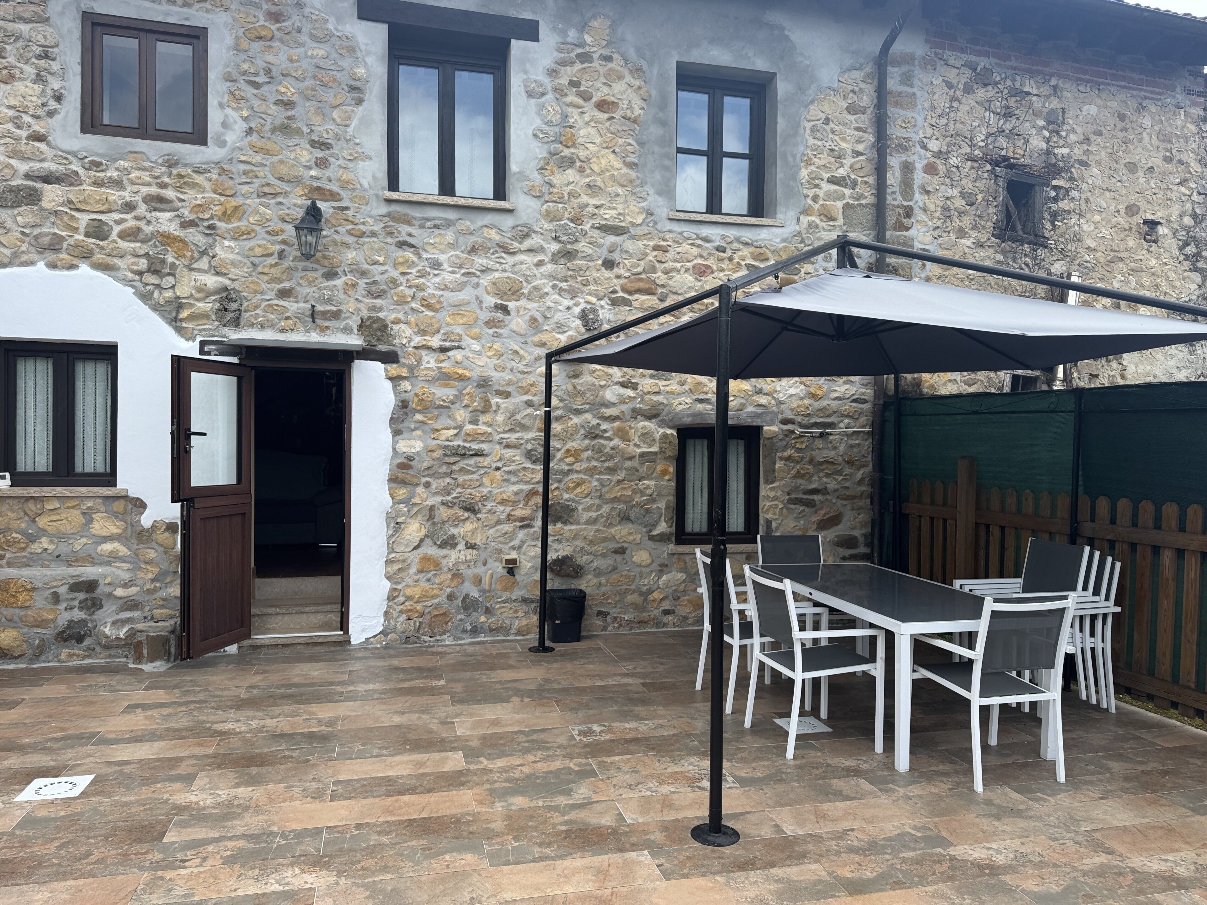 A stone building with a patio area featuring a table and chairs, a door, and a window.