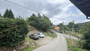 A rural road with two parked cars, surrounded by greenery and a house in the distance. - El Valle de la Reina House (Romillo)