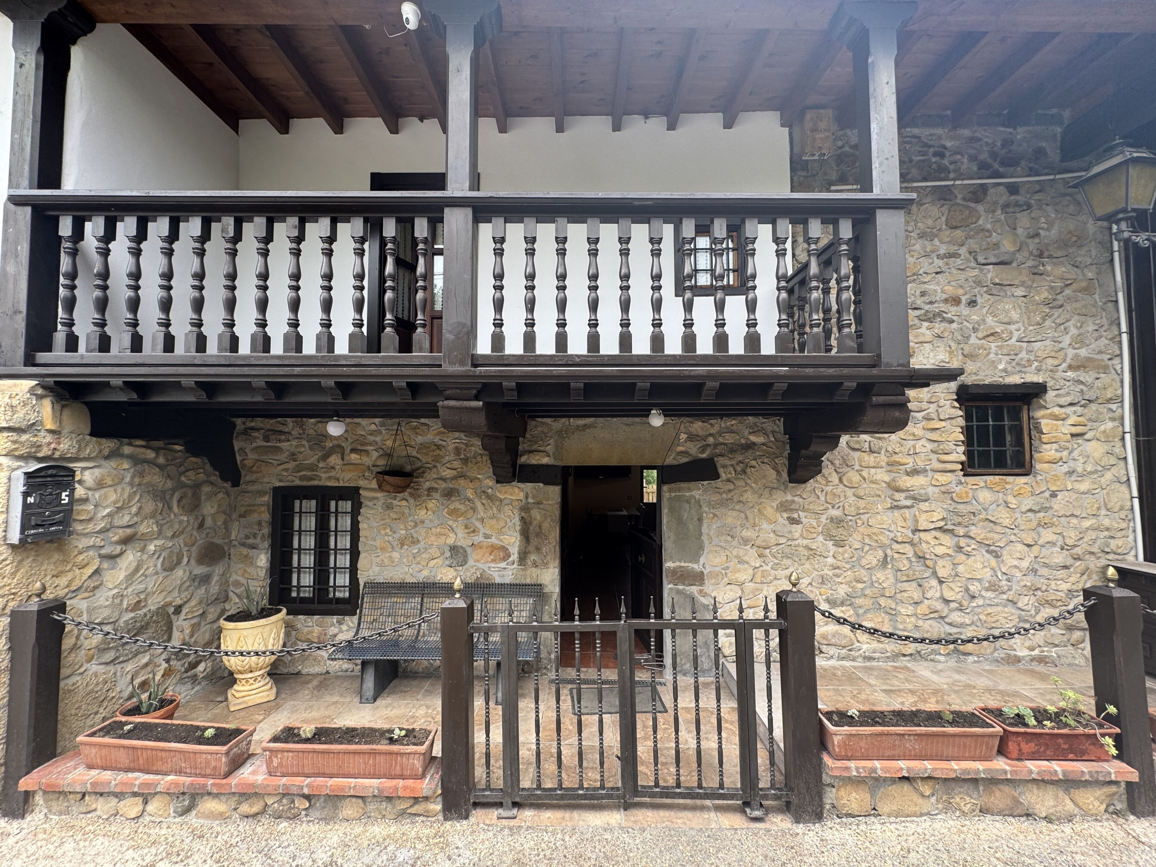 Un bâtiment en pierre doté d’un balcon, d’une boîte aux lettres et de plantes en pot.