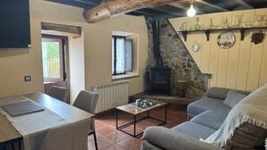 A cozy living room with a fireplace, a dining table, and a sofa. - El Valle de la Reina House (Romillo)