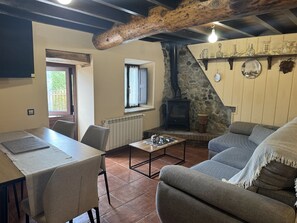 A cozy living room with a fireplace, a dining table, and a sofa. - El Valle de la Reina House (Romillo)
