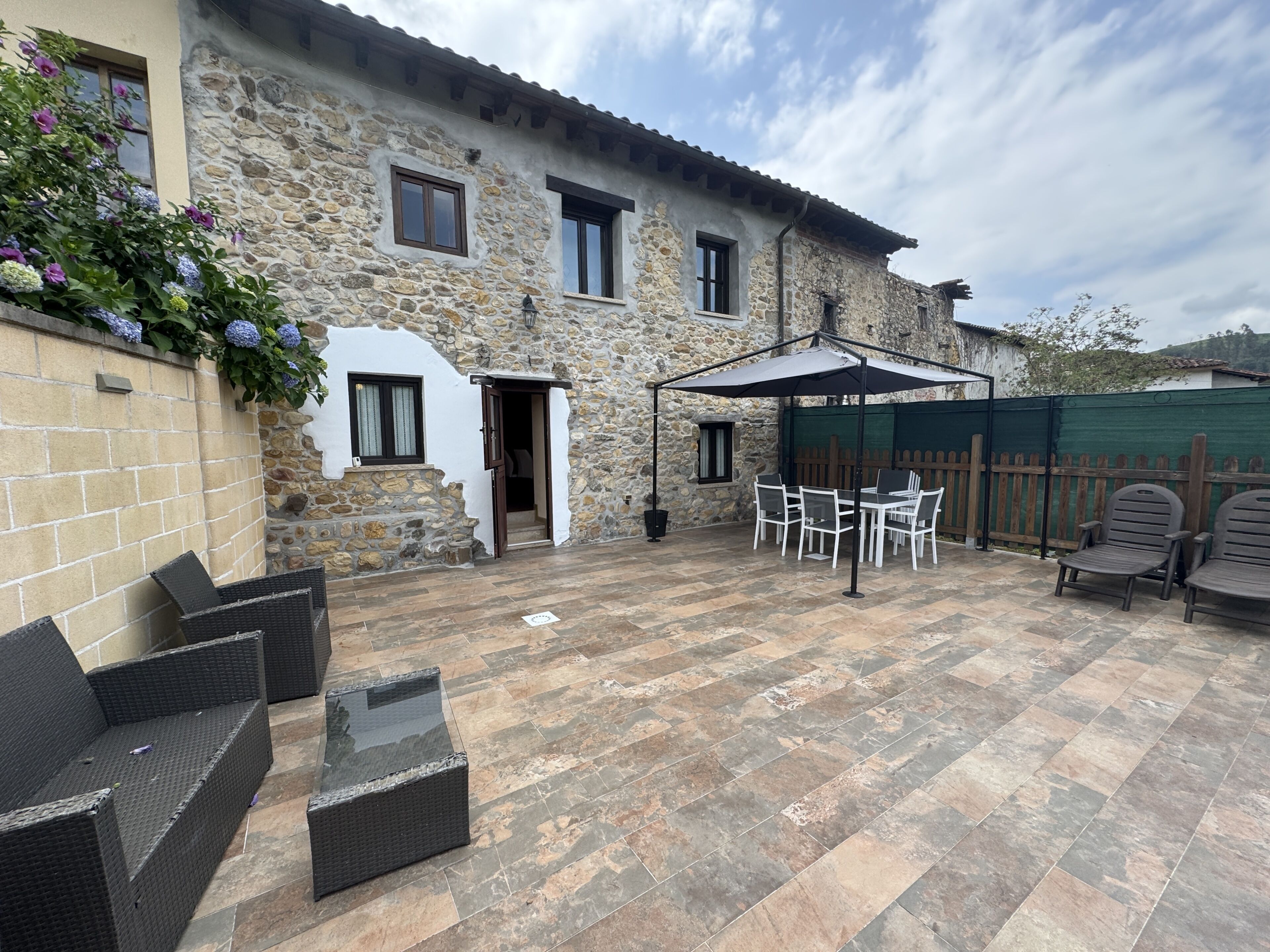 Un bâtiment en pierre doté d’un patio aménagé avec du mobilier d’extérieur et un espace salon couvert.