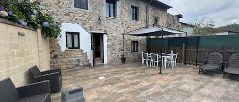 Un bâtiment en pierre doté d’un patio aménagé avec du mobilier d’extérieur et un espace salon couvert.