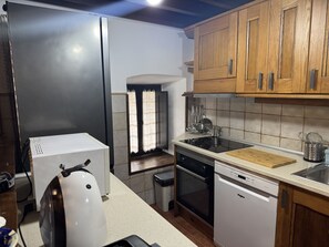 Eine Küche mit Kühlschrank, Backofen, Geschirrspüler und Holzschränken.