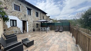 A stone building with a patio area featuring outdoor furniture and a covered seating area. - El Valle de la Reina House (Romillo)