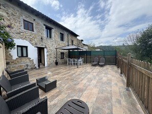 A stone building with a patio area featuring outdoor furniture and a covered seating area. - El Valle de la Reina House (Romillo)