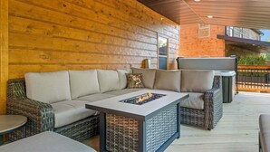 Ein Sitzbereich im Freien mit einer Couch, einem Tisch mit Feuerstelle und einem Grill.