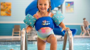 Ein Kind im Schwimmbecken mit Schwimmweste und Zeichentrickfiguren.