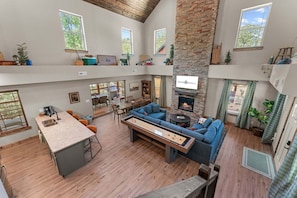 A spacious living area with a fireplace, a dining area, and a kitchen with a bar. - Cozy Tall Timbers Retreat_Pvt Hot Tub_Near Lazy River_Free Tickets_Shuffleboard_Arcade (Hollister)