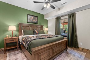 A bedroom with a wooden bed, green walls, a ceiling fan, and a window with curtains. - Cozy Tall Timbers Retreat_Pvt Hot Tub_Near Lazy River_Free Tickets_Shuffleboard_Arcade (Hollister)