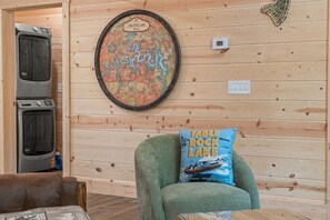 Ein Zimmer mit einer Holzwand, einer gerahmten Karte des Table Rock Sees, einem grünen Sessel mit Kissen und einer Waschmaschine.