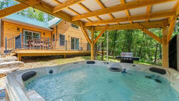A wooden cabin with a hot tub and barbecue area.