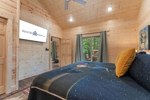 Une chambre dans une cabane en bois, avec un lit, des rideaux, un ventilateur de plafond et une enseigne indiquant RENTBRUNSON.COM.