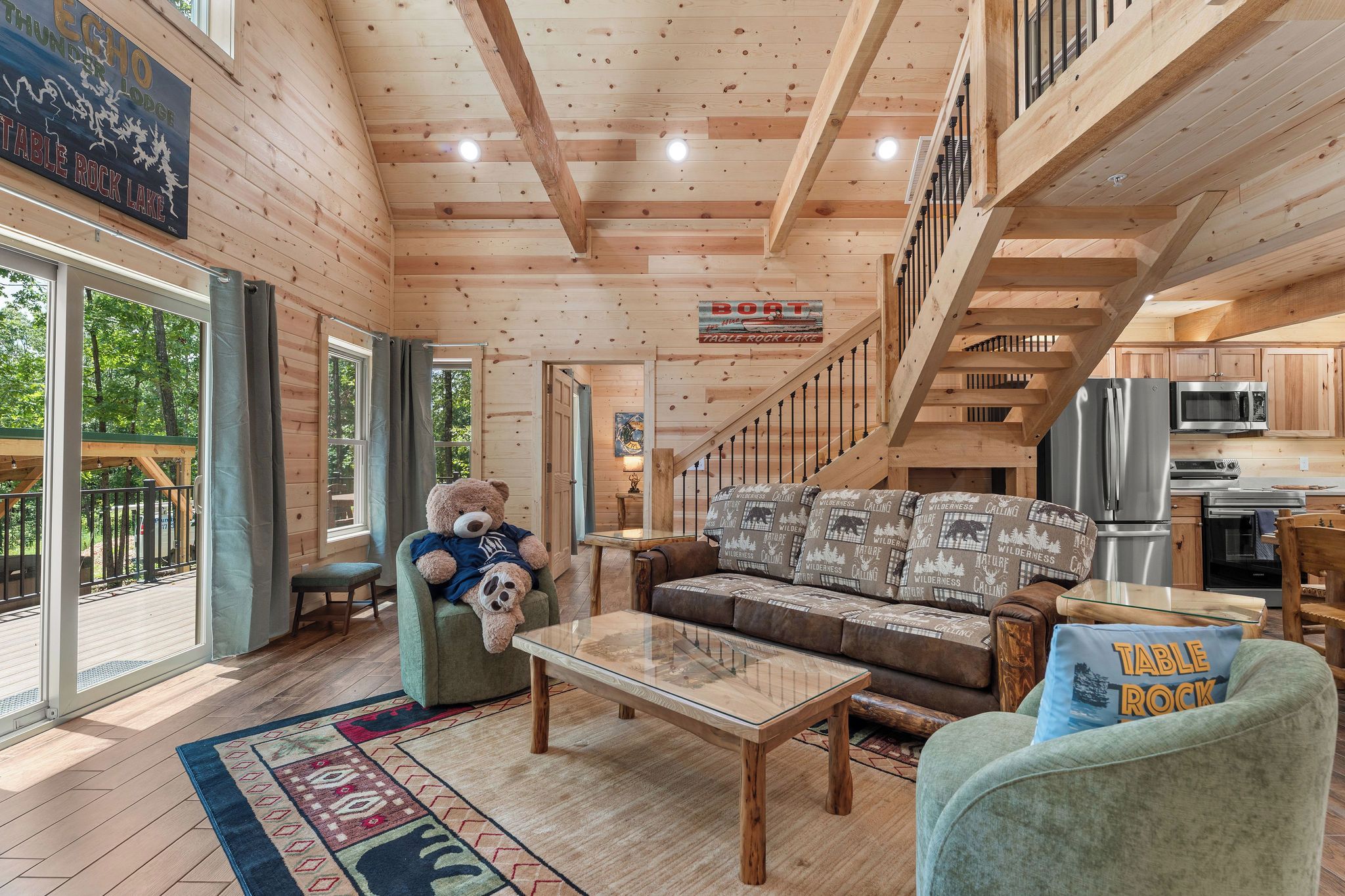 A spacious cabin interior with a wooden ceiling, a sofa set, a dining table, and a kitchen area.