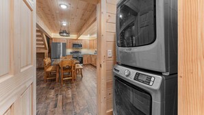 A compact kitchen with a built-in oven and microwave, wooden flooring, and a dining area with a table and chairs. - Cabin Near Thunder Ridge & Big Cedar_Private Hot Tub_Free Attraction Tickets_Bonus Loft (Ridgedale)