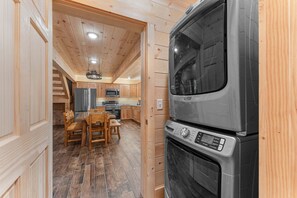 Eine kompakte Küche mit Einbauofen und Mikrowelle, Holzboden sowie Essbereich mit Tisch und Stühlen.