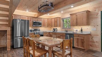 A modern kitchen with wooden cabinets, stainless steel appliances, and a glass-top dining table.