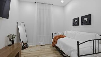 A bedroom with a bed, a bedside table, a mirror, and a wall-mounted artwork.
