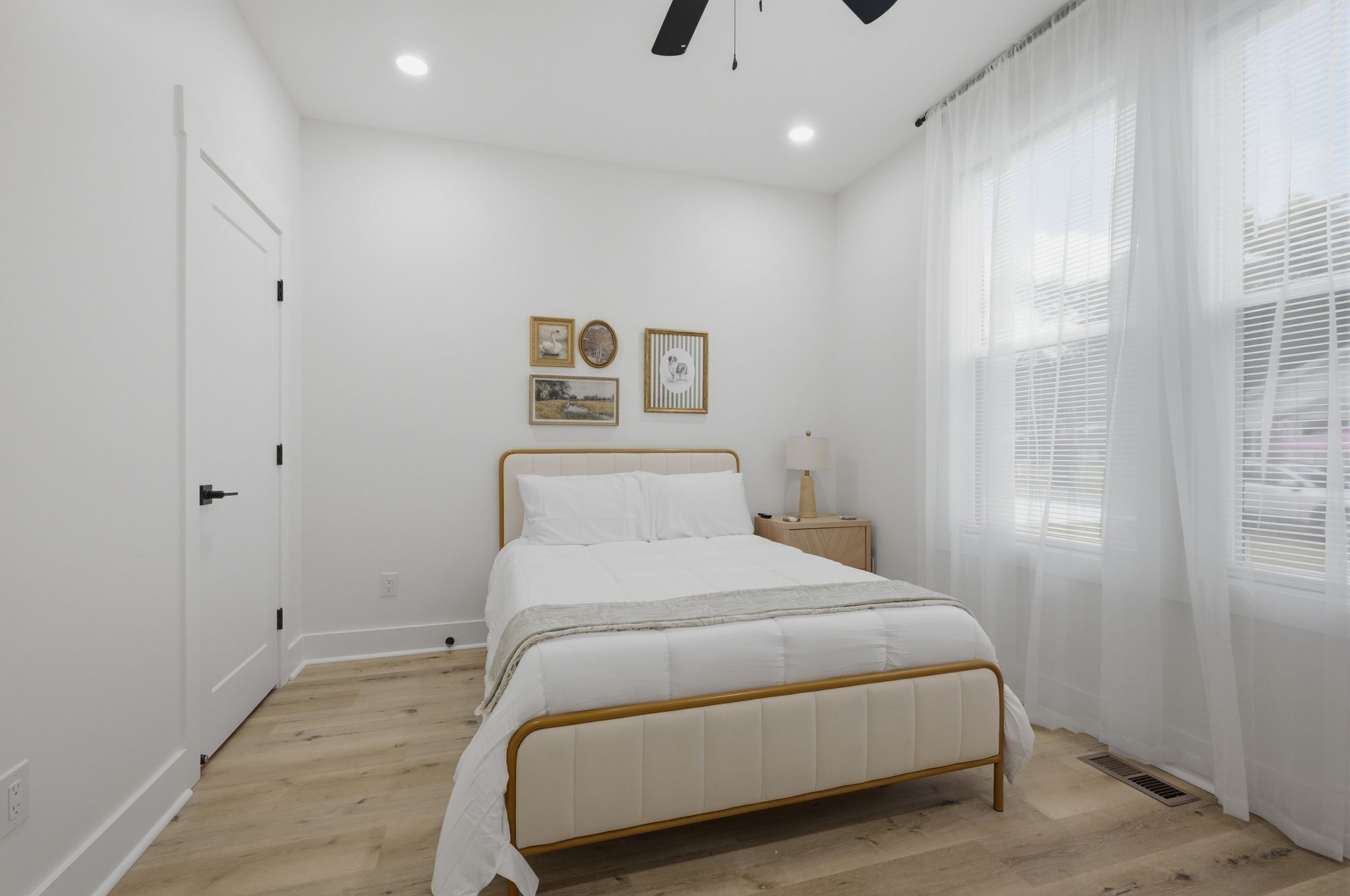 Une chambre à coucher avec un lit, une table de chevet, une lampe et une fenêtre avec des stores.