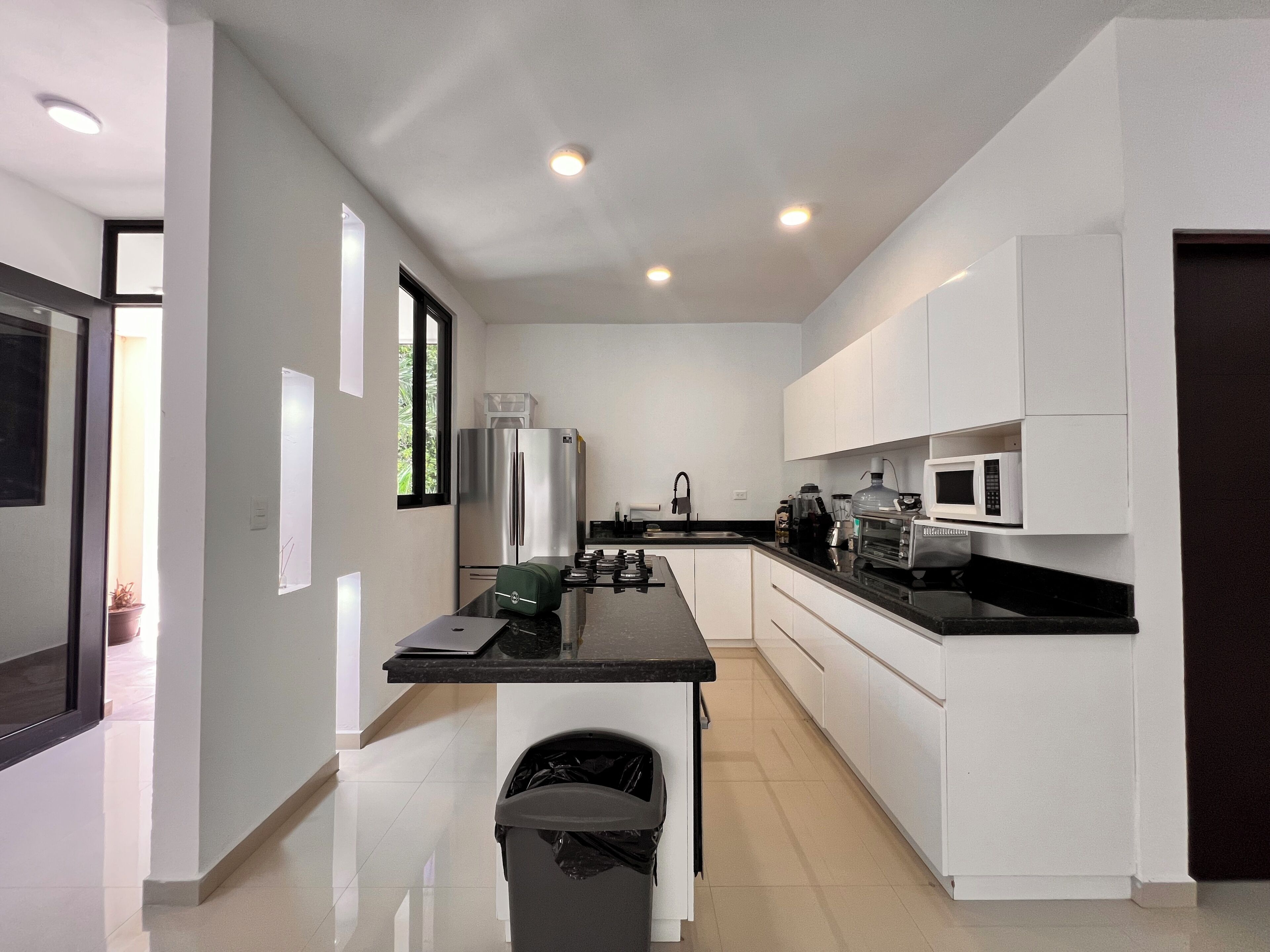 A modern kitchen with white cabinets, a black countertop, stainless steel appliances, and a window providing natural light.