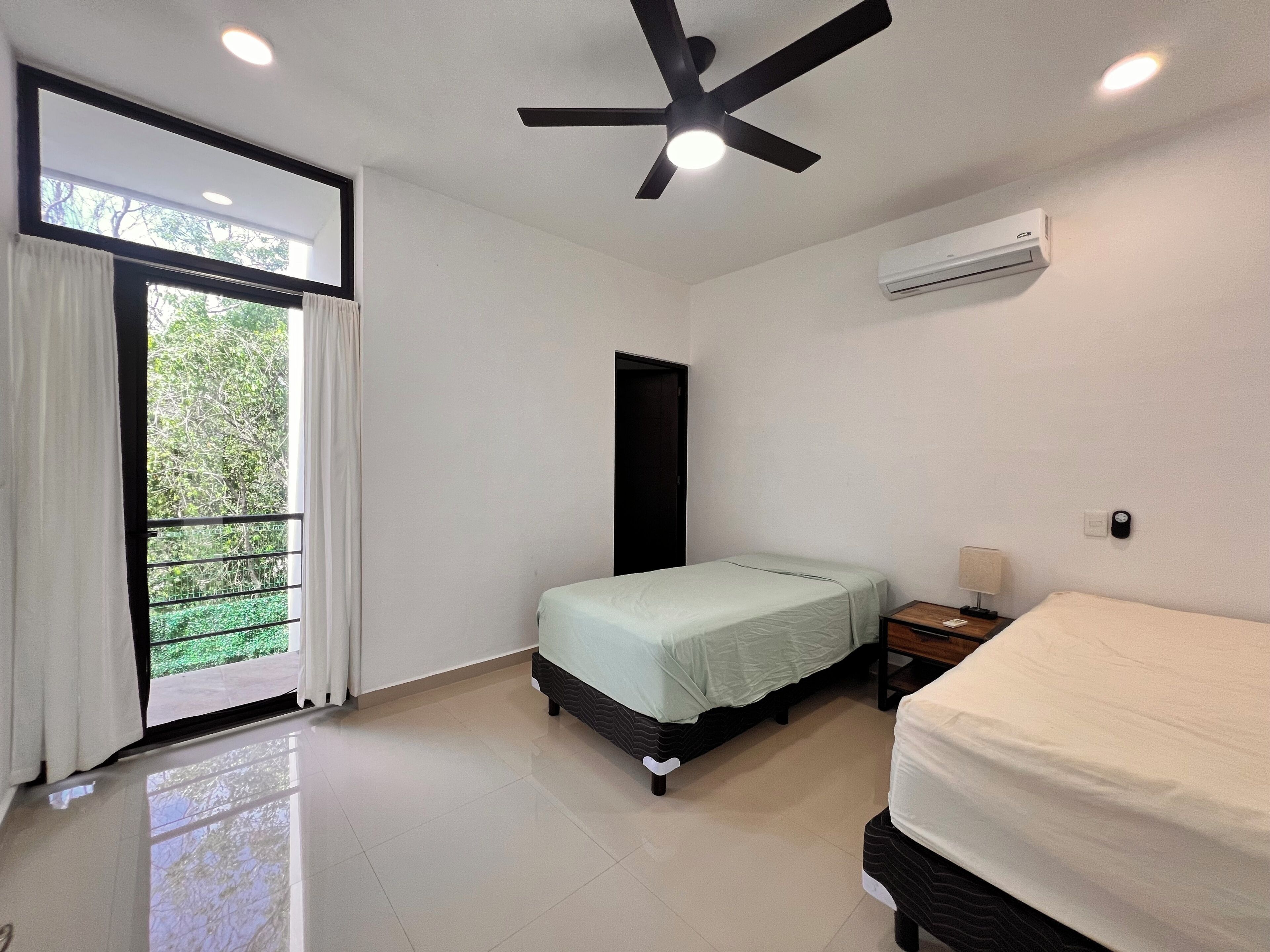 Quarto com cama, mesa de cabeceira, ventoinha no teto e ar condicionado.