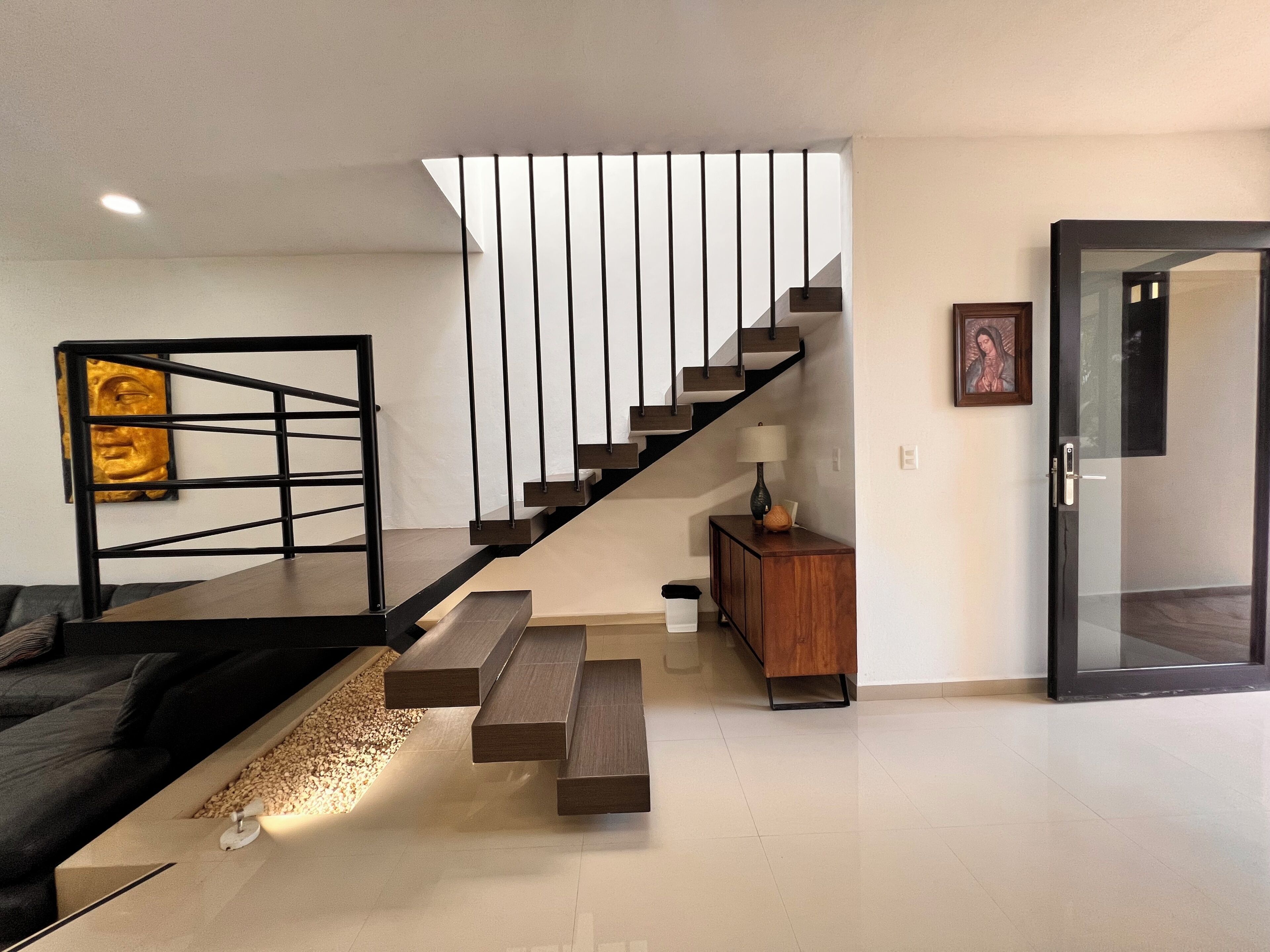 Uma sala de estar moderna com uma escada, um sofá, uma mesa de centro e um pequeno armário.