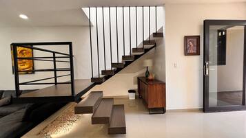 Uma sala de estar moderna com uma escada, um sofá, uma mesa de centro e um pequeno armário.