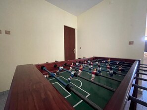 Een tafelvoetbaltafel in een ruimte met effen muren en een houten deur.