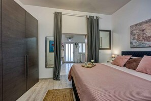 Ein Schlafzimmer mit einem Bett, einem Kleiderschrank, einem Spiegel und einem Bild an der Wand.