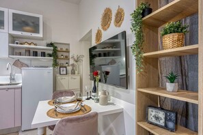 Eine moderne Küche mit weißen Schränken, einem eingebauten Backofen und einem Essbereich mit einem weißen Tisch und rosafarbenen Stühlen.