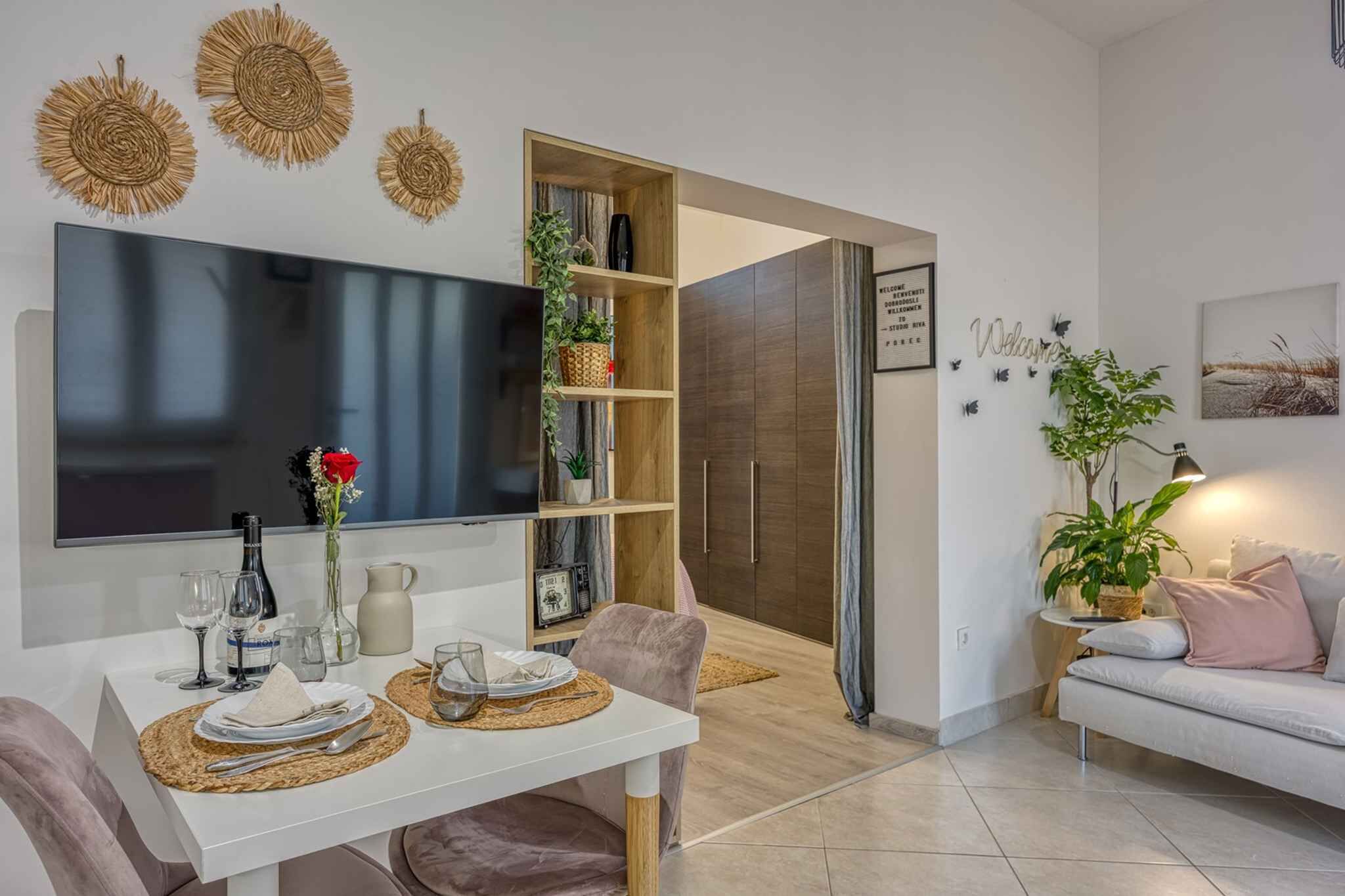 A modern living room with a dining area, a large flat-screen TV, a sofa, and a coffee table.