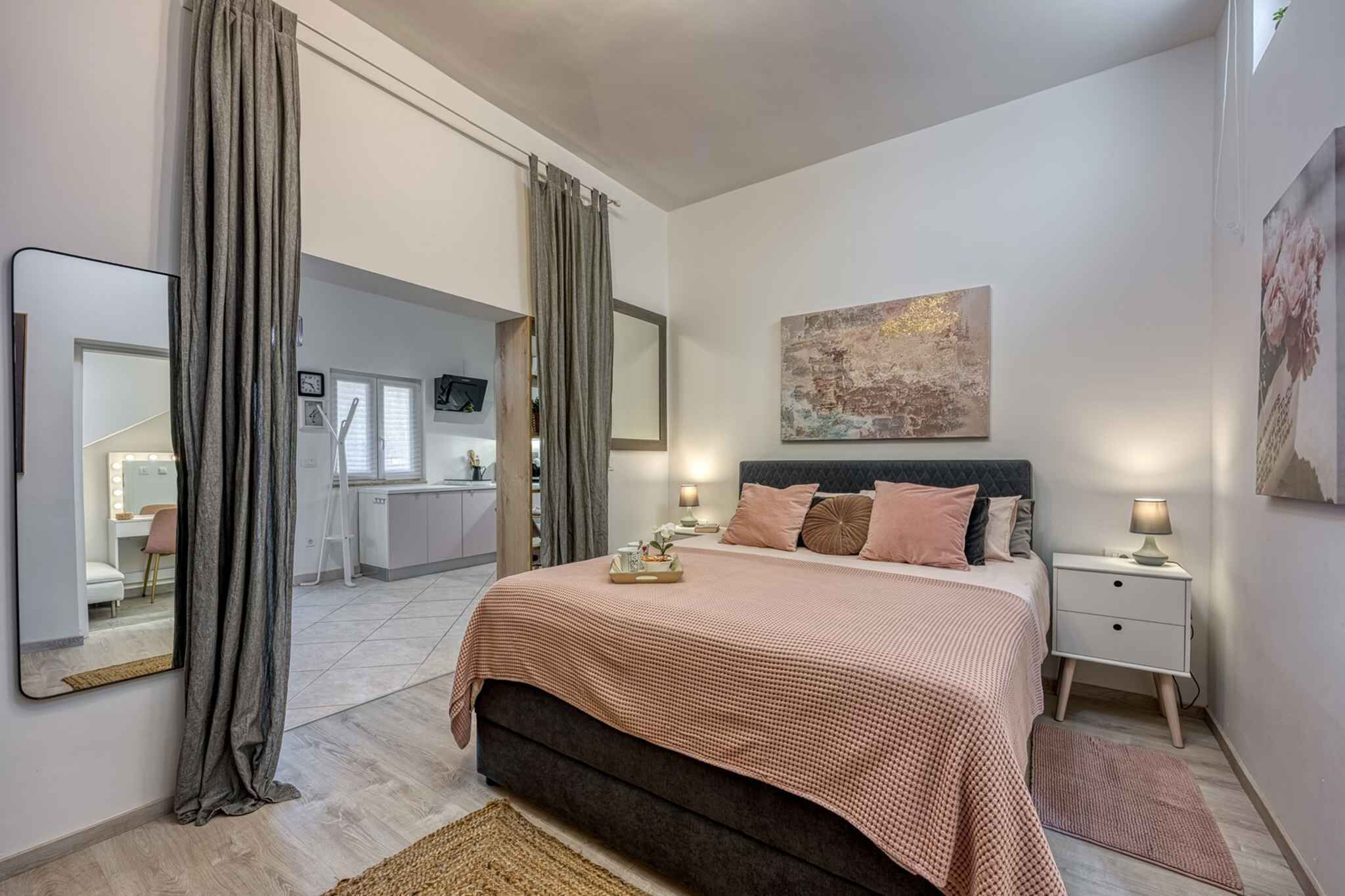 A bedroom with a bed, a nightstand, a bedside lamp, a large mirror, and a painting on the wall.