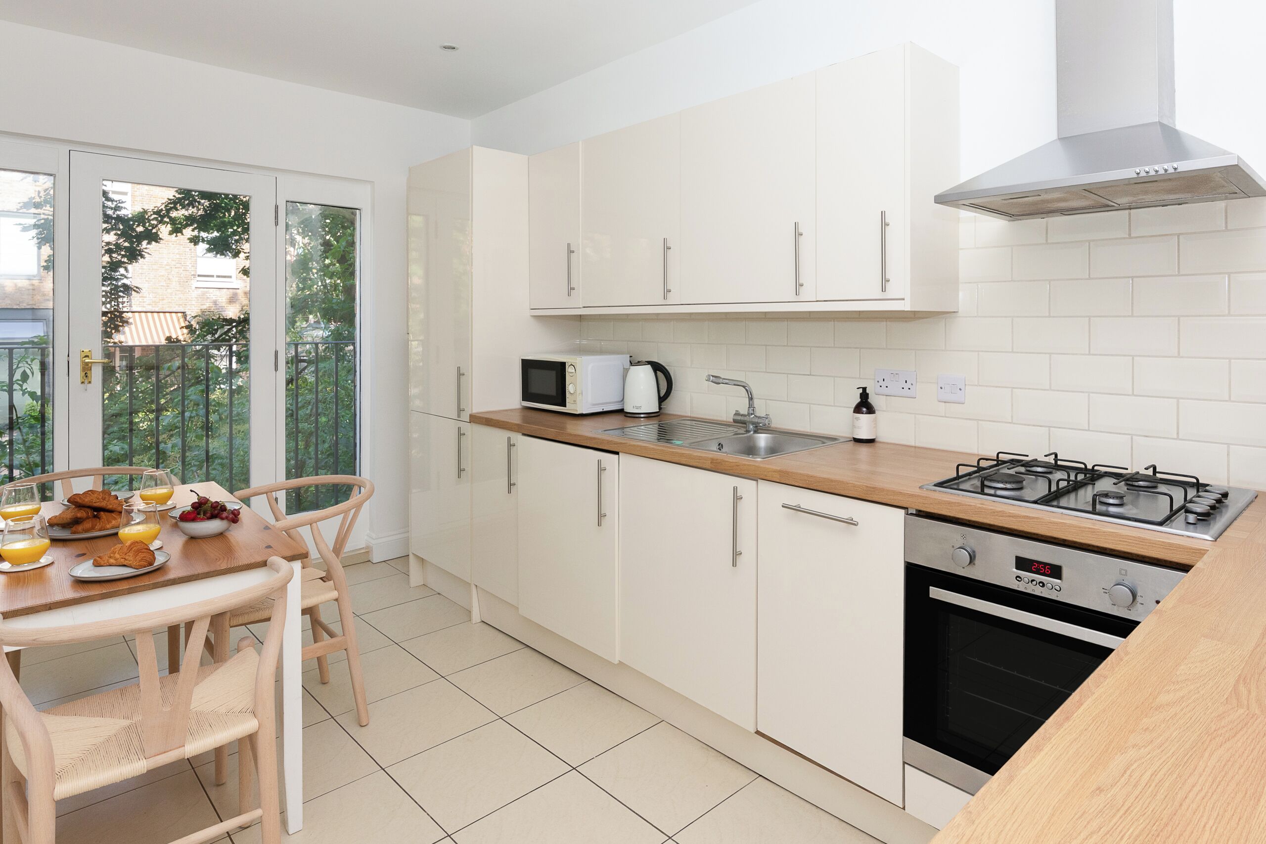 Une cuisine moderne avec des meubles blancs, une cuisinière à gaz, un four à micro-ondes et un évier.