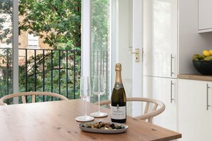 Una mesa de madera con una botella de vino, dos copas de vino y un bol de aceitunas.