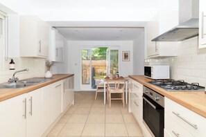 A compact kitchen with a central island, a stove, and a sink. - Notting Hill Grove Apartments (London)