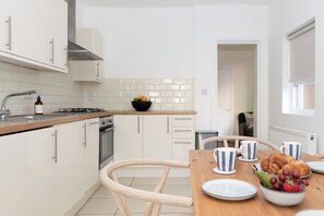 A modern kitchen with white cabinetry, a wooden countertop, and a dining area with a table set for breakfast.