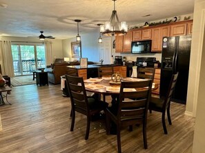 A modern kitchen with wooden cabinets, a black refrigerator, and a dining area with a round table and chairs. - 3BR lakefront condo with pool, balcony, and resort amenities (Hollister)