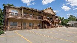 Ein mehrstöckiges Motel mit einer zentralen Treppe, Balkonen und einem Parkplatz.