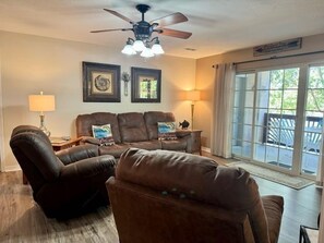 A living room with a brown leather sofa set, a ceiling fan, and a large window with a view. - Lakefront Condo  with Dock Access (Hollister)