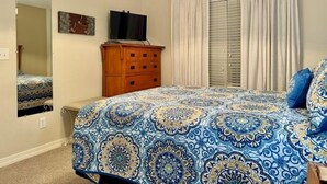 A bedroom with a bed, a dresser, a television, and a window with curtains. - Lakefront Condo  with Dock Access (Hollister)