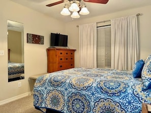 A bedroom with a bed, a dresser, a television, and a window with curtains. - Lakefront Condo  with Dock Access (Hollister)