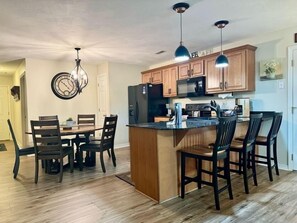 A kitchen with wooden cabinets, a central island with bar stools, and pendant lighting. - Lakefront Condo  with Dock Access (Hollister)
