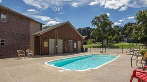 A pool area with a building, outdoor seating, and a fenced yard. - Lakefront Condo  with Dock Access (Hollister)