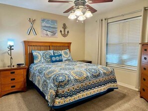 A bedroom with a bed, wooden headboard, bedside tables, a ceiling fan, and a window with curtains. - Lakefront Condo  with Dock Access (Hollister)