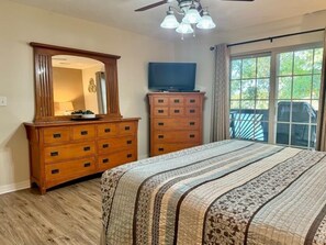 A bedroom with a large bed, wooden dresser, and a television on a stand. - Lakefront Condo  with Dock Access (Hollister)
