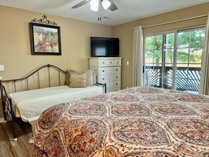 A bedroom with a bed, a television, a dresser, and a balcony with a view. - Lakefront 3BR condo at Table Rock Lake with pool, patio, and WiFi. (Hollister)