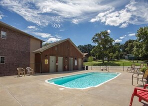 A pool area with a brick building, a wooden structure, and outdoor seating. - Lakefront 3BR condo at Table Rock Lake with pool, patio, and WiFi. (Hollister)