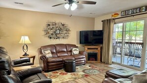 A living room with a fireplace, leather sofas, a television, and a large window.